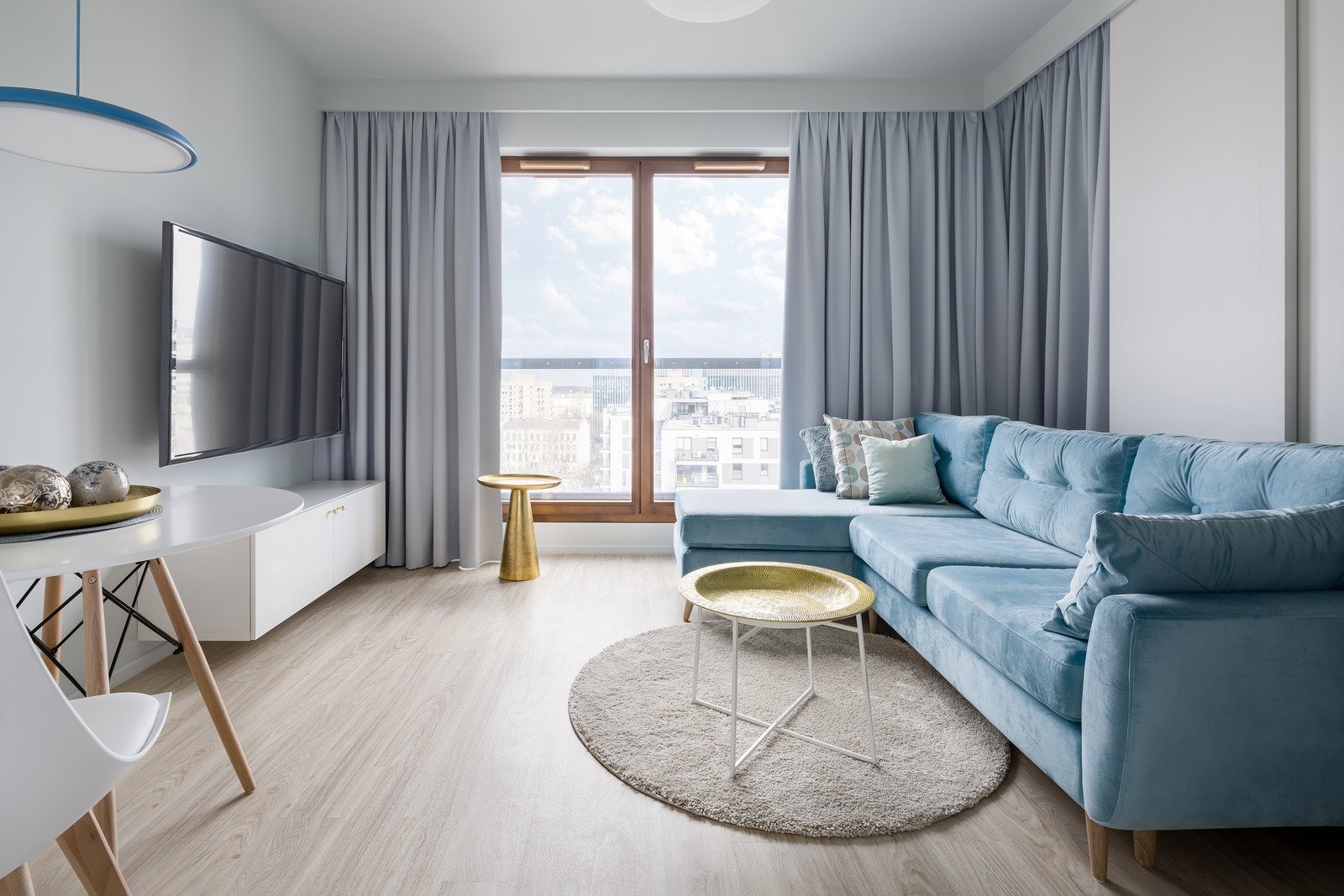 minimalistyczne mieszkanie urządzone w ciepłych barwach, błękitna sofa, białe meble