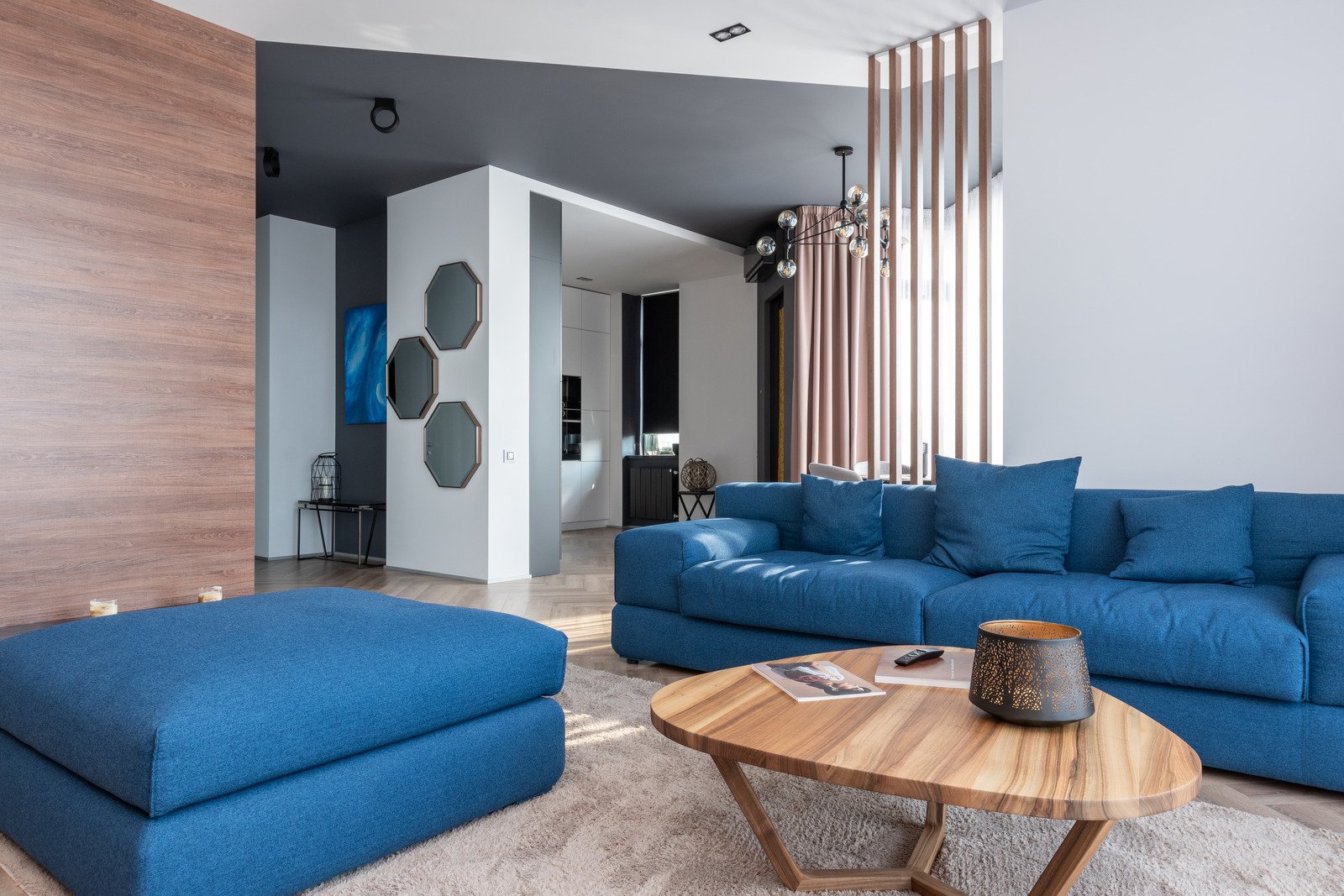 nowoczesny salon z niebieskimi kanapami i owalnym drewnianym stolikiem
