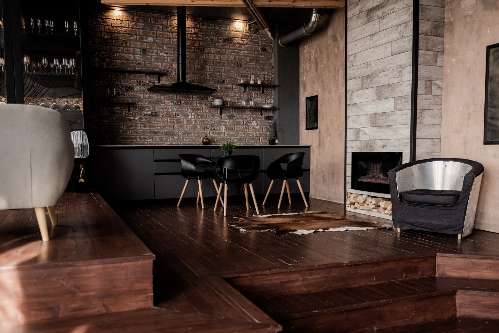 drewniana podłoga, murowana  ściana, czarne meble kuchenne